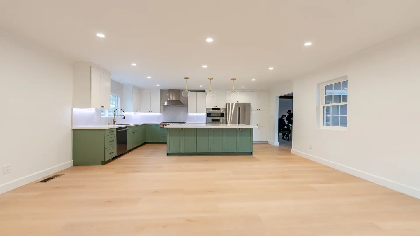 Open kitchen with sage-green cabinets, a large island and wide-plank floors in San Jose