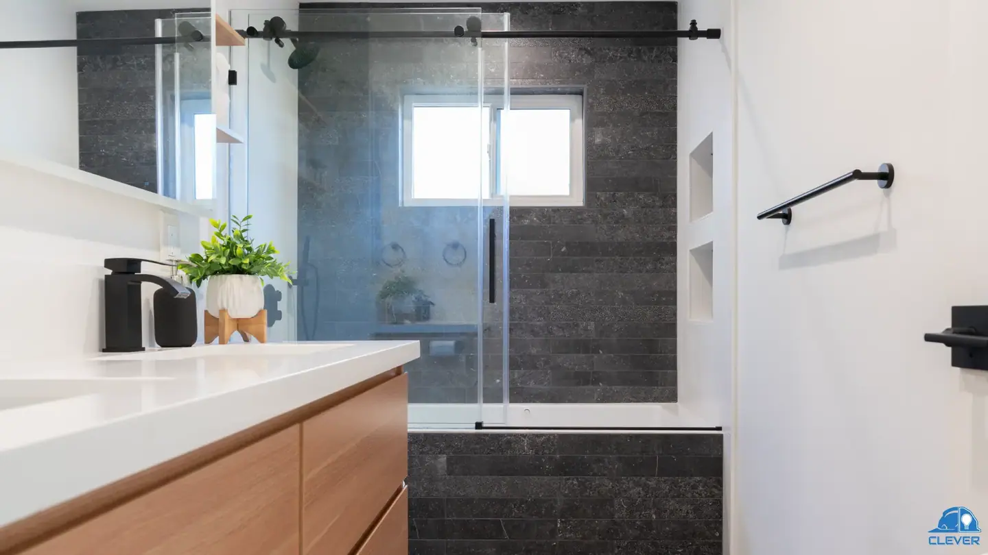 Bathroom with a wood floating vanity and dark stone tub surround
