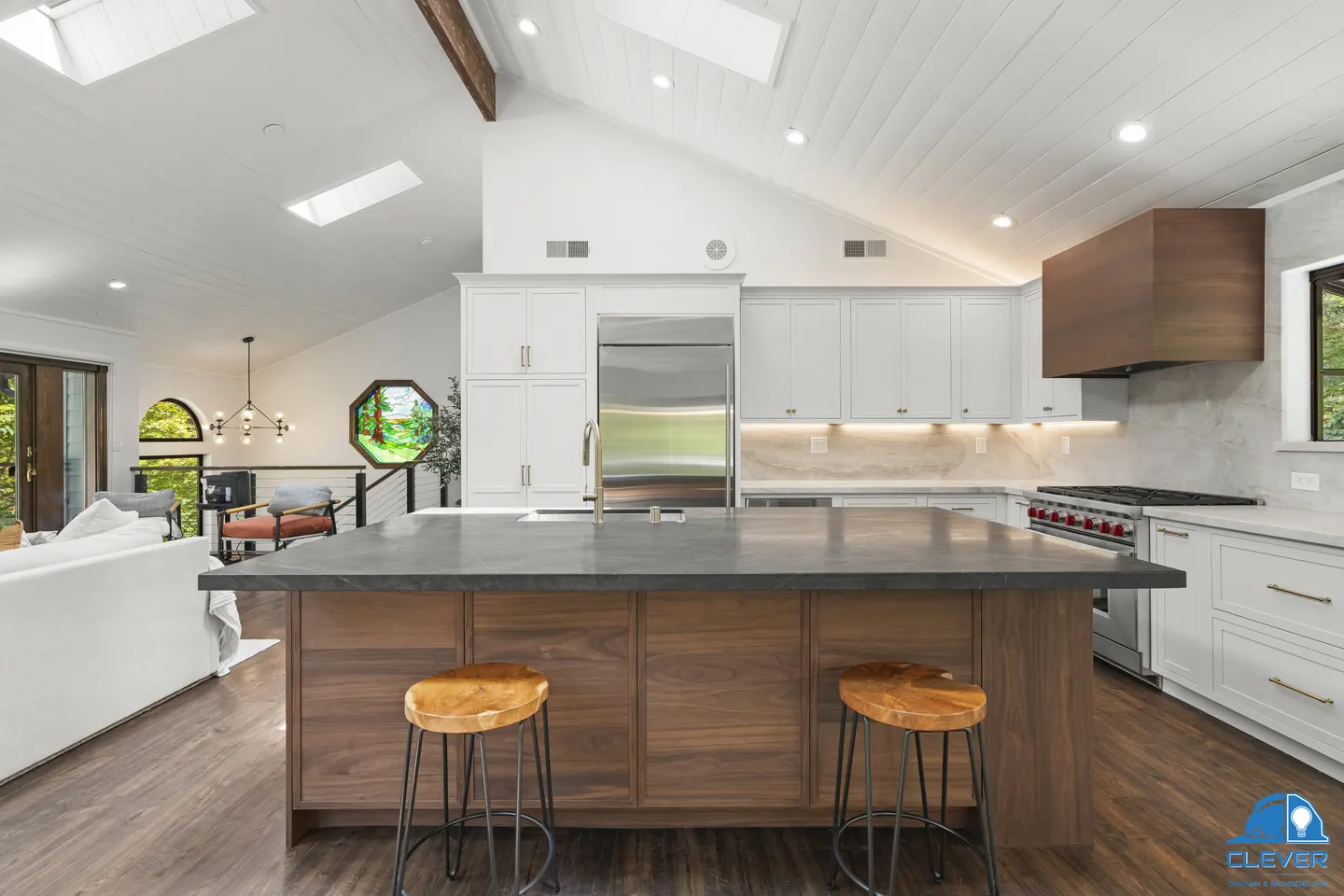 Walnut island with a dark stone top and wood stools, with a built-in refrigerator and pro-style range beyond, kitchen and bath remodel in Los Gatos, CA