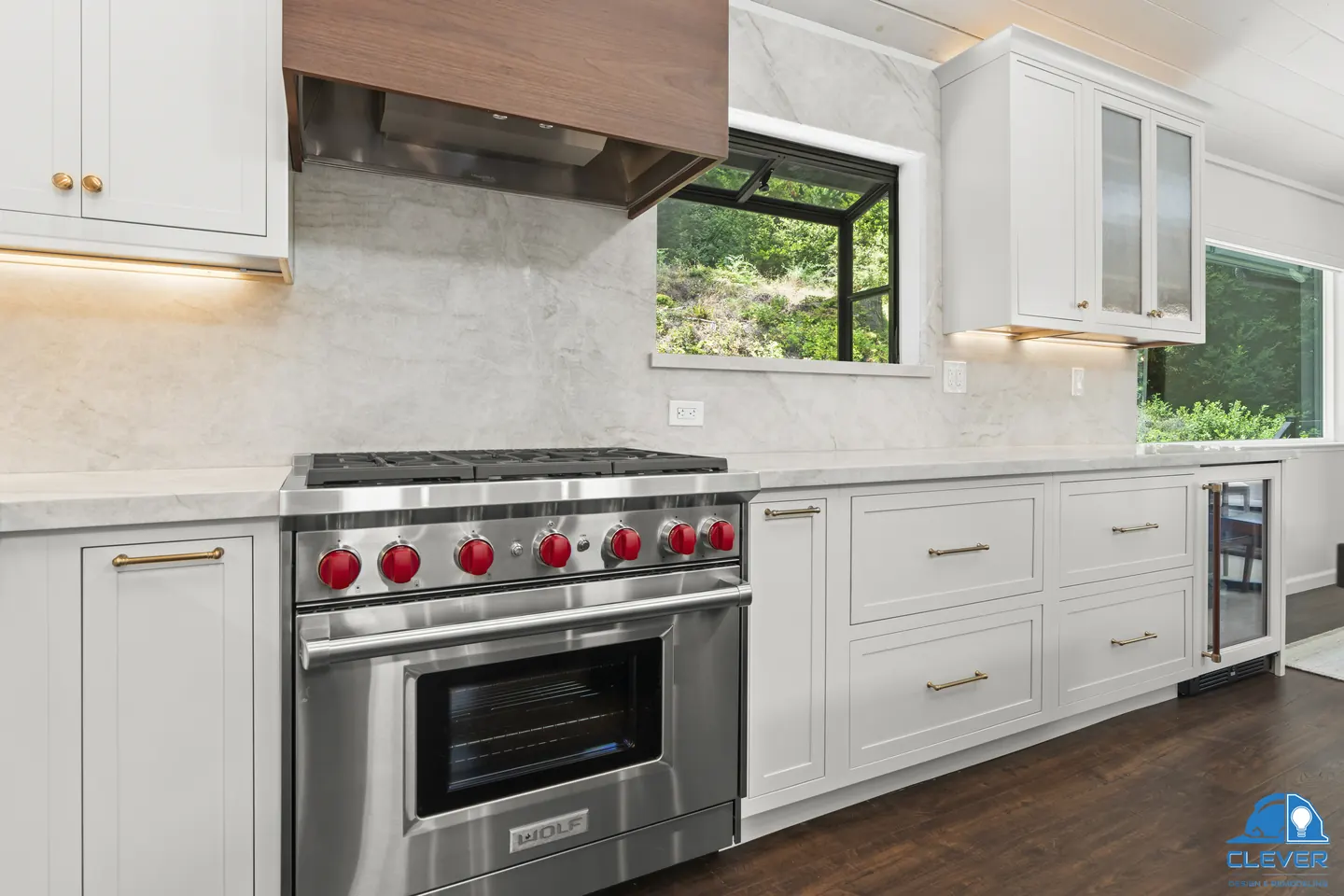 Pro-style range with red knobs under a walnut hood, with a stone slab backsplash and a garden window, kitchen and bath remodel in Los Gatos, CA