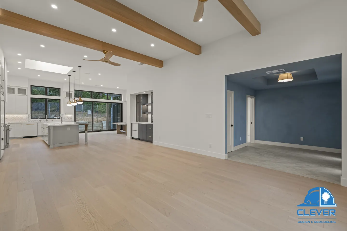 Beamed living room with white oak floors, opening to the kitchen and a blue-walled entry, whole-home remodel in Saratoga, CA